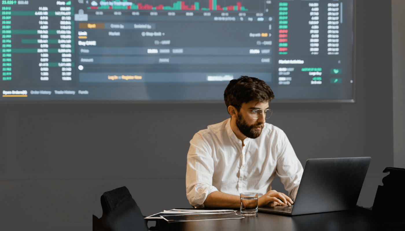 A data analyst sitting at a table wearing a white shirt, using a laptop while drinking a glass of water, working with PI Vision and using PI CompressionMD to better use data. (2) (1)