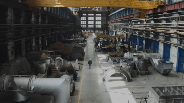 A view from a large gas plant showing different gas processing equipment with a worker walking down the middle aisle (1)
