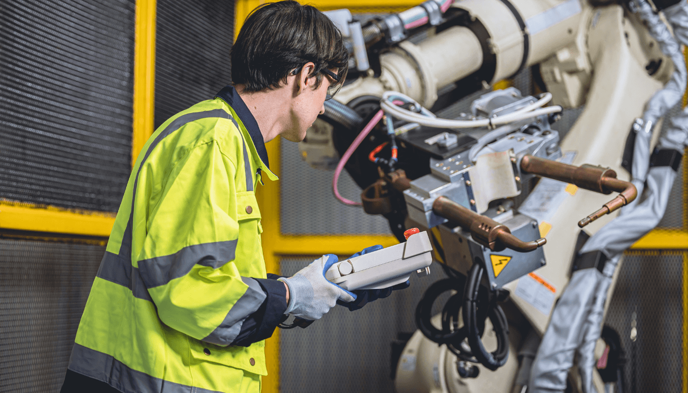 Industrial worker with a yellow jacket checking automated equipment
