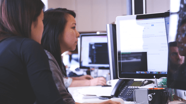 Two women looking at a computer screen monitoring applications via PI Systems (1)