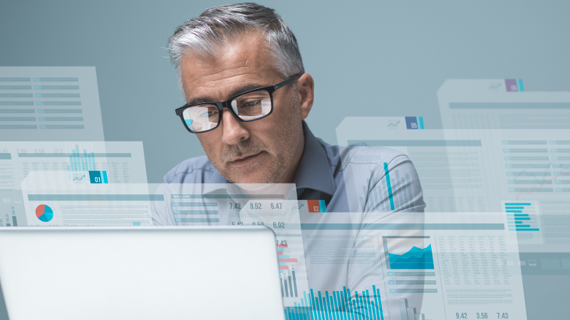 Man with glasses analyzing data on a computer screen.