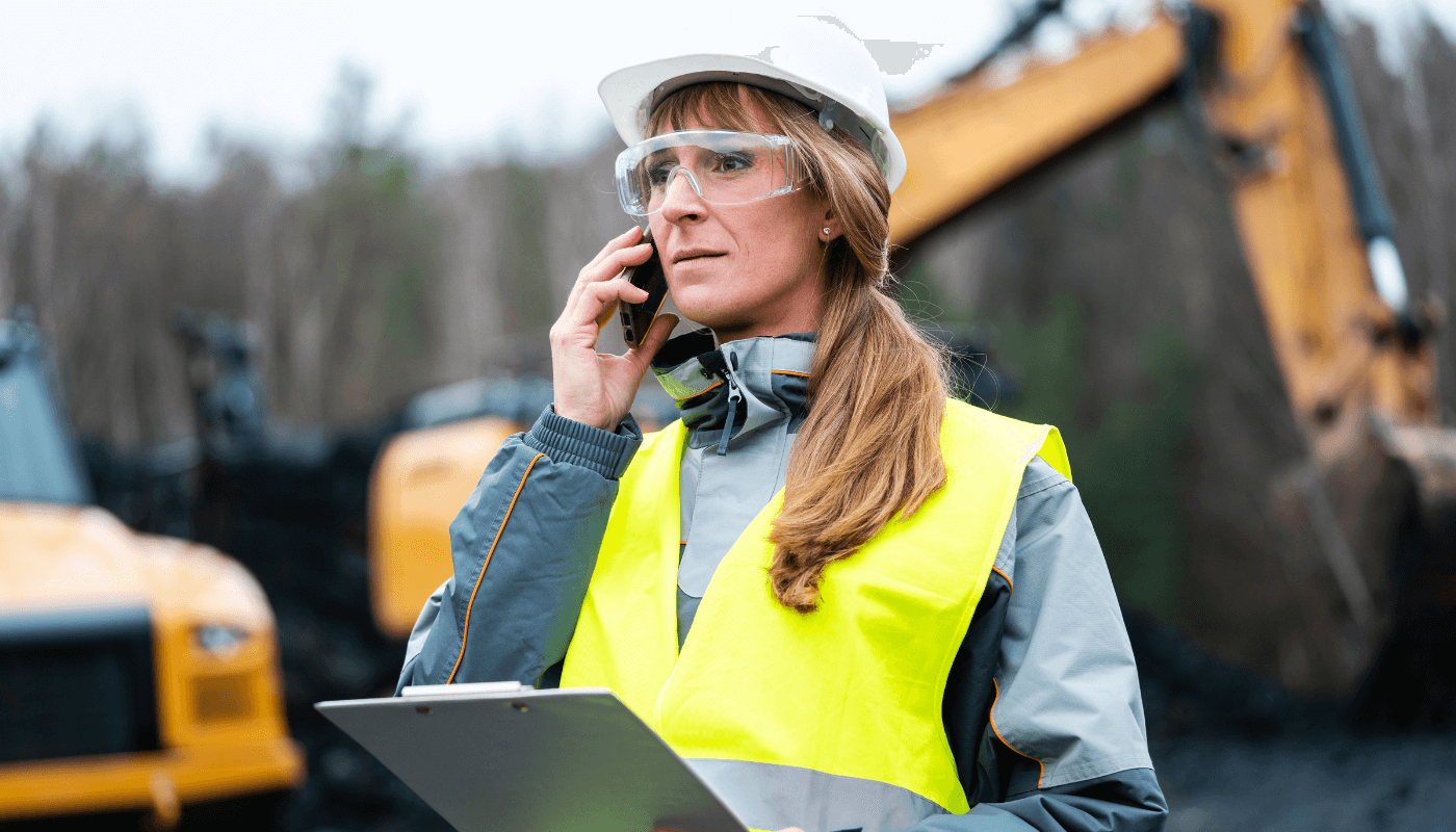 Manufacturing engineer wearing hi-res vest and safety goggles on the phone