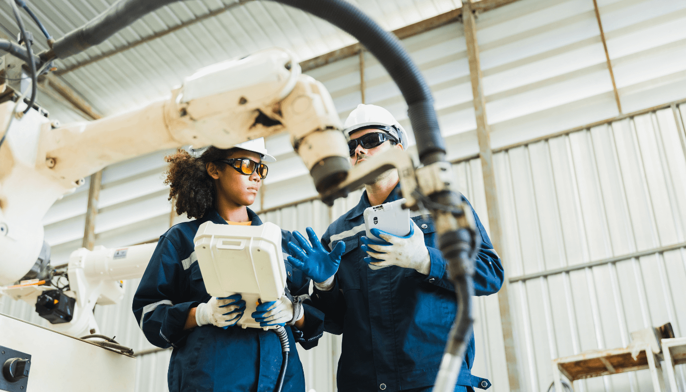 Two industrial workers wearing safety gear checking automated equpiment.