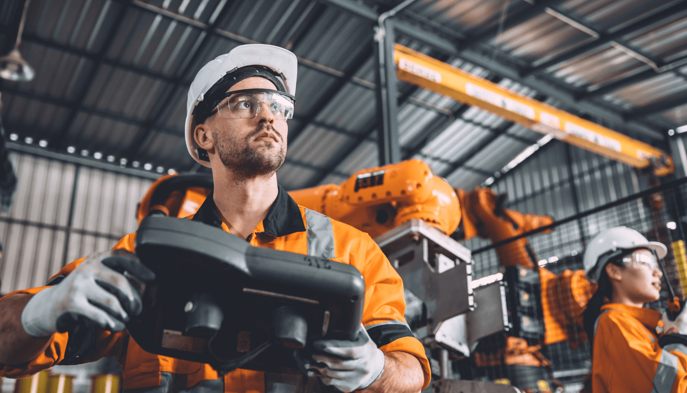 Worker with a white hard hat and orange jacket running a system analysis on equpiment.