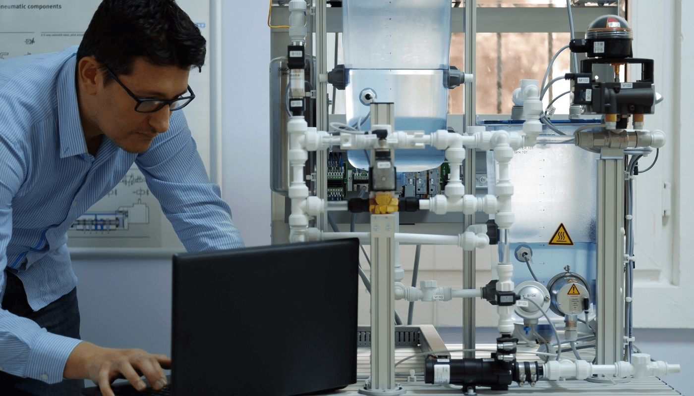 An engineer installing PLC programming from a computer into machines