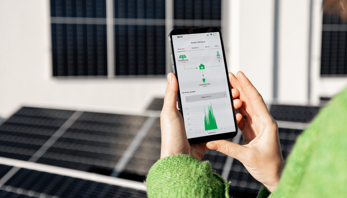 A woman in a green sweater checking energy management statistics on a smart phone.