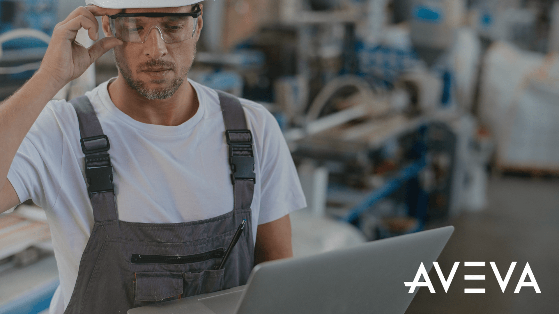 A male worker in a factory looking at data on a computer while holding his glasses (1)