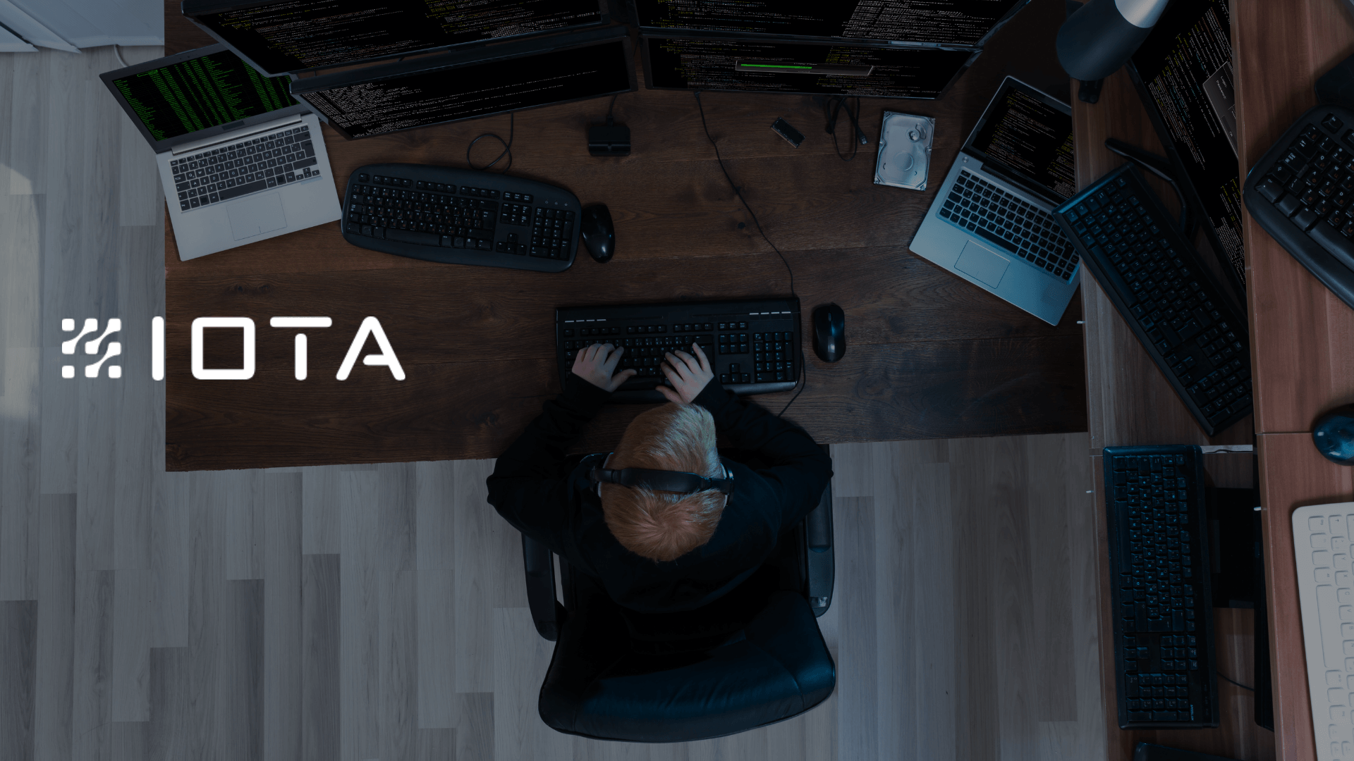 A person sitting at a computer desk with multiple computer screens working on data (1)
